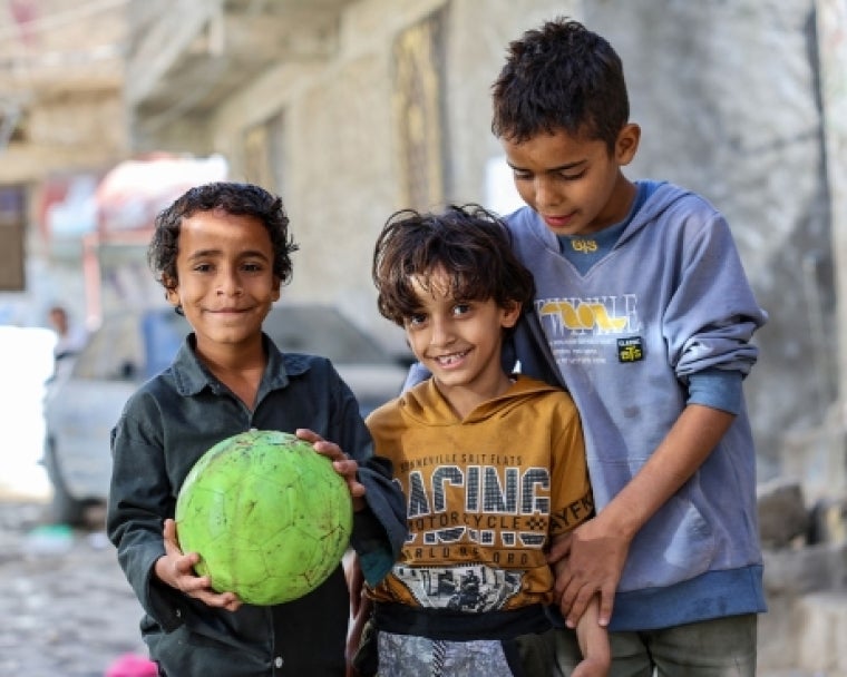 Bilal smiling and holding a soccer ball with his brothers after cleft surgery