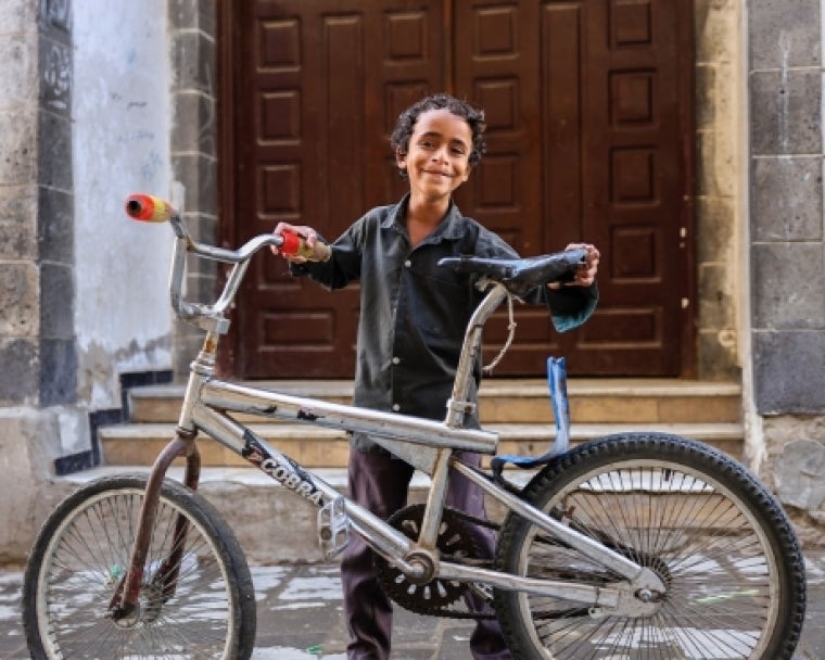 Bilal smiling and holding his bike after cleft surgery